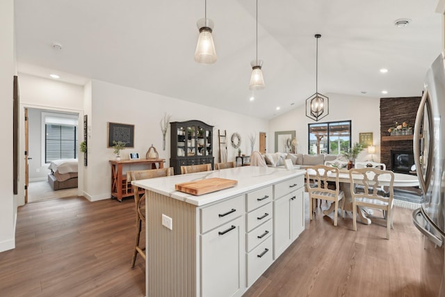 25822 Emerson Ct, Wyoming, MN 55092 - kitchen with open floor plan, a kitchen bar, wood finished floors, vaulted ceiling, and white cabinets