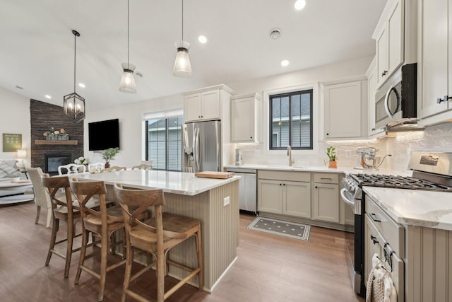 25822 Emerson Ct, Wyoming, MN 55092 - kitchen featuring appliances with stainless steel finishes, backsplash, a fireplace, a sink, and lofted ceiling