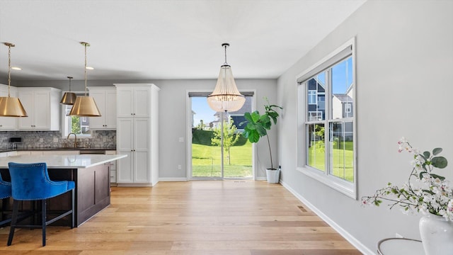 6455 Timber Arch Dr, Chaska, MN 55318 - kitchen featuring decorative backsplash, white cabinets, light wood-style floors, and plenty of natural light
