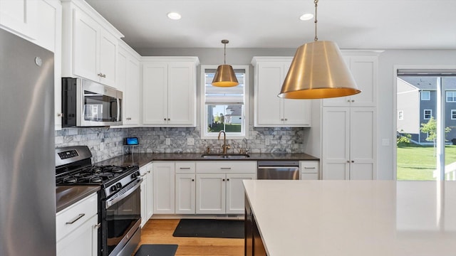 6455 Timber Arch Dr, Chaska, MN 55318 - kitchen with stainless steel appliances, a sink, dark countertops, decorative backsplash, and white cabinetry