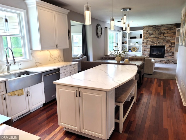 10402 Indiana Ave N, Brooklyn Park, MN 55443 - kitchen with stainless steel dishwasher, a sink, dark wood finished floors, white cabinetry, and a kitchen island