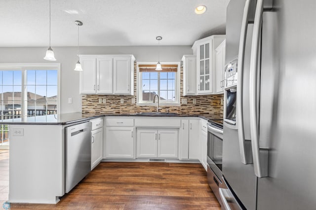 1586 Baywood Dr, Fargo, ND 58078 - kitchen featuring appliances with stainless steel finishes, a sink, a peninsula, dark countertops, and decorative backsplash