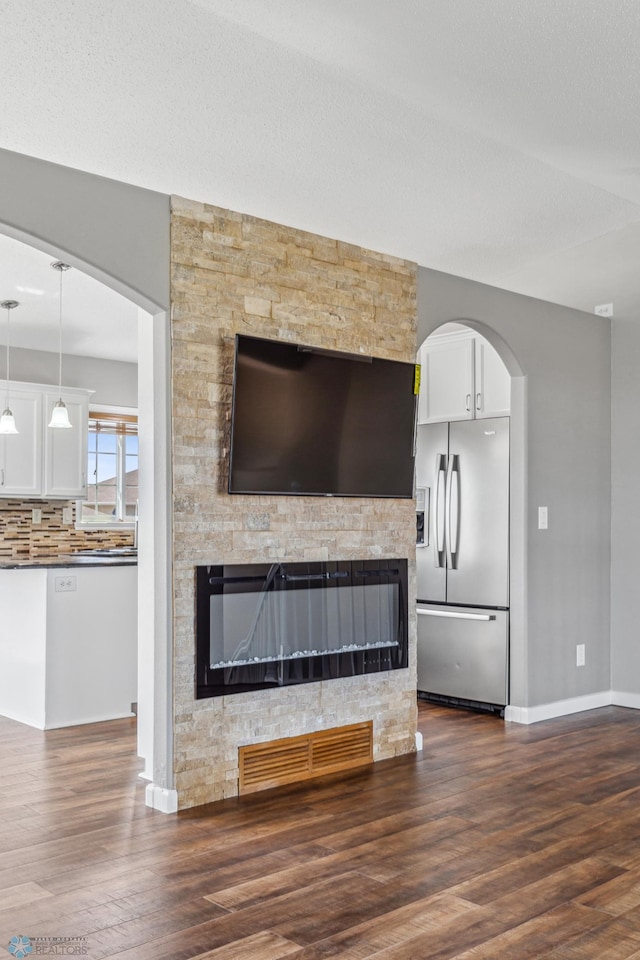 1586 Baywood Dr, Fargo, ND 58078 - detailed view of stainless steel fridge with ice dispenser, baseboards, wood finished floors, and a stone fireplace