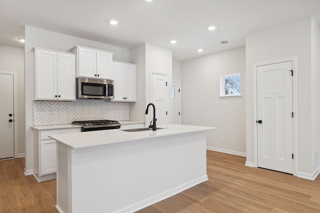 23217 Creekview Ct, Rogers, MN 55374 - kitchen with stainless steel appliances, a sink, backsplash, light wood-style flooring, and a kitchen island with sink