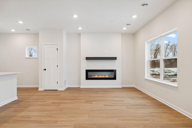 23217 Creekview Ct, Rogers, MN 55374 - unfurnished living room with recessed lighting, a glass covered fireplace, light wood-style floors, and baseboards