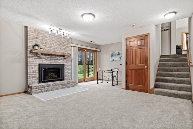 4985 142nd Ln NW, Ramsey, MN 55303 - unfurnished living room with a textured ceiling, carpet flooring, track lighting, stairs, and a brick fireplace