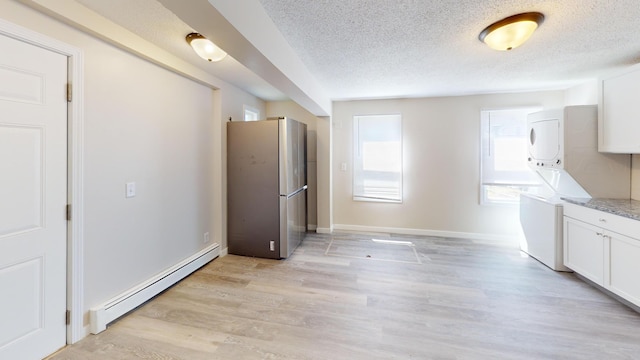 594 Charles Ave, Saint Paul, MN 55103 - kitchen featuring freestanding refrigerator, stacked washer / dryer, a baseboard radiator, a textured ceiling, and white cabinetry