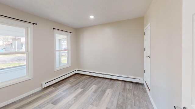 594 Charles Ave, Saint Paul, MN 55103 - spare room featuring light wood-type flooring, a baseboard radiator, baseboards, and recessed lighting