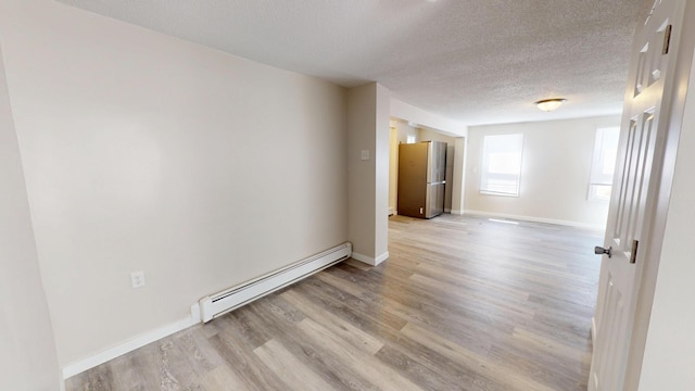 594 Charles Ave, Saint Paul, MN 55103 - empty room featuring a baseboard radiator, a textured ceiling, light wood-style flooring, and baseboards