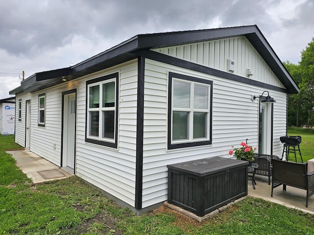 2011/2 10th Ave SE, Pipestone, MN 56164 - view of side of property with board and batten siding, a patio area, and a lawn