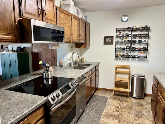 252 Miller St, Spicer, MN 56288 - kitchen featuring stainless steel appliances, a sink, baseboards, stone finish flooring, and brown cabinetry