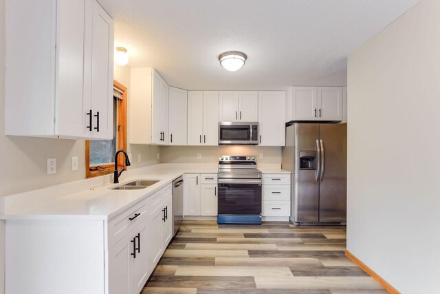 11622 Rio Loma Ln, Burnsville, MN 55337 - kitchen featuring appliances with stainless steel finishes, a sink, white cabinetry, light wood finished floors, and light countertops