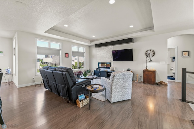 3784 Bell Blvd E, West Fargo, ND 58078 - living area featuring a tray ceiling, wood finished floors, arched walkways, a textured ceiling, and baseboards