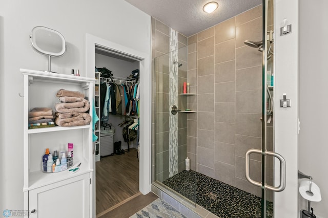 3784 Bell Blvd E, West Fargo, ND 58078 - bathroom featuring a shower stall, a spacious closet, wood finished floors, and a textured ceiling