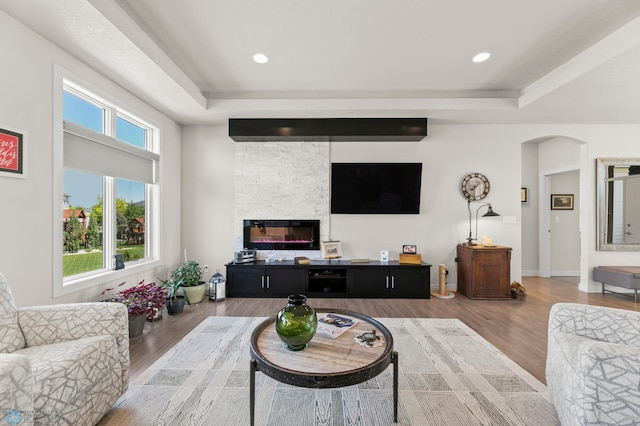 3784 Bell Blvd E, West Fargo, ND 58078 - living room with a raised ceiling, arched walkways, a stone fireplace, wood finished floors, and recessed lighting
