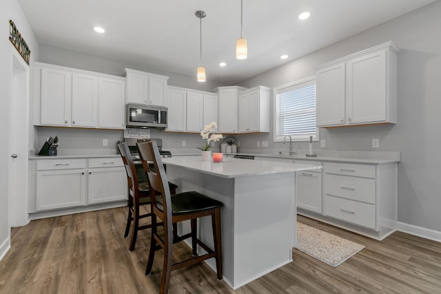12905 Jewell Cir NE, Blaine, MN 55449 - kitchen featuring appliances with stainless steel finishes, a sink, white cabinets, a kitchen bar, and a center island