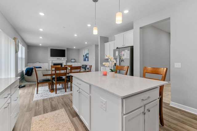 12905 Jewell Cir NE, Blaine, MN 55449 - kitchen featuring stainless steel fridge, a kitchen island, light wood finished floors, white cabinetry, and recessed lighting