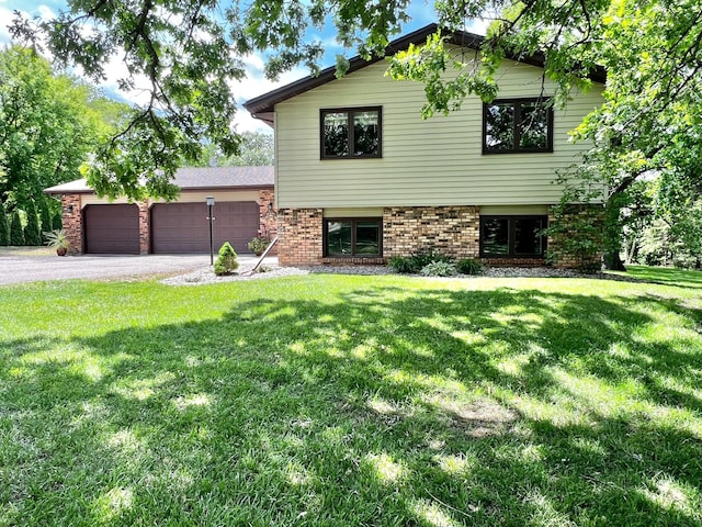 17300 Baseline Ave, Sand Creek Twp, MN 55352 - split level home featuring a garage, asphalt driveway, a front lawn, and brick siding