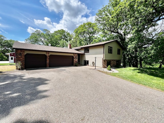 17300 Baseline Ave, Sand Creek Twp, MN 55352 - split level home with an attached garage, asphalt driveway, a chimney, and a front yard