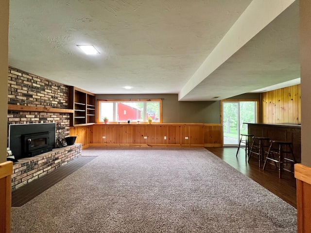 17300 Baseline Ave, Sand Creek Twp, MN 55352 - unfurnished living room with wooden walls, a textured ceiling, built in features, wood finished floors, and wainscoting