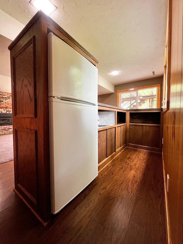 17300 Baseline Ave, Sand Creek Twp, MN 55352 - kitchen with freestanding refrigerator, dark wood finished floors, wooden walls, and a textured ceiling
