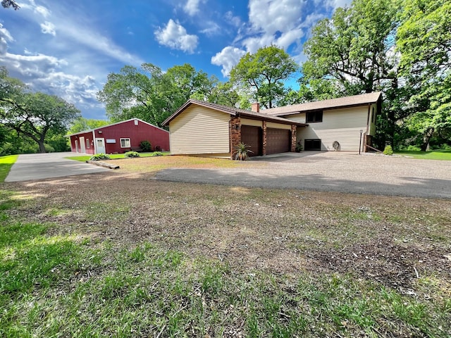 17300 Baseline Ave, Sand Creek Twp, MN 55352 - view of front of house with driveway, a garage, a chimney, and central air condition unit