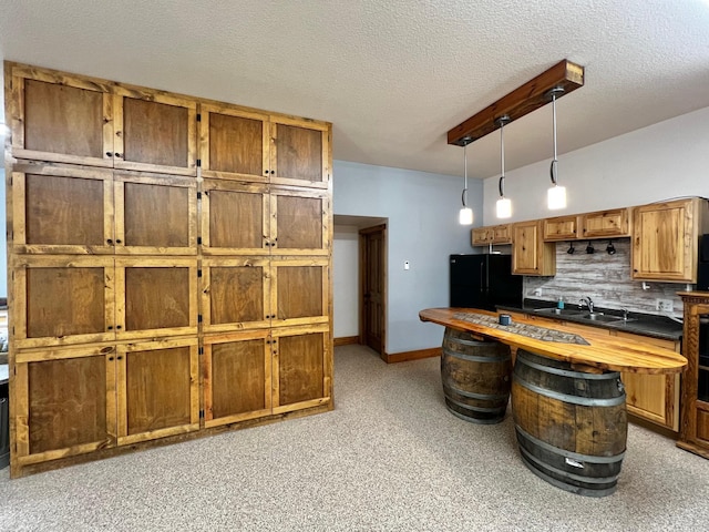 17300 Baseline Ave, Sand Creek Twp, MN 55352 - kitchen with freestanding refrigerator, a sink, decorative light fixtures, a textured ceiling, and brown cabinetry