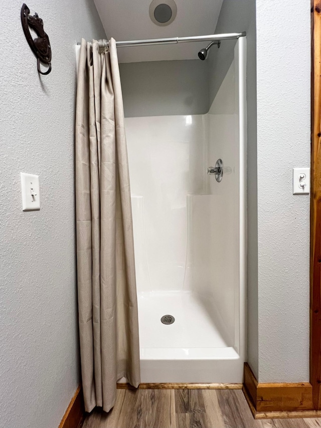 17300 Baseline Ave, Sand Creek Twp, MN 55352 - full bath with wood finished floors, a shower with curtain, a textured wall, and baseboards