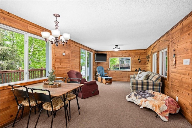 2614 Leroy Rd, Eveleth, MN 55734 - carpeted dining space featuring wooden walls, a textured ceiling, and a chandelier