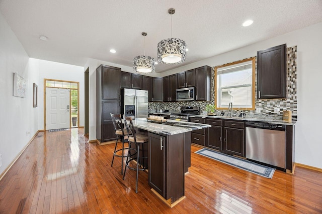 12332 3rd St NE, Blaine, MN 55434 - kitchen featuring stainless steel appliances, a breakfast bar area, tasteful backsplash, dark brown cabinets, and recessed lighting