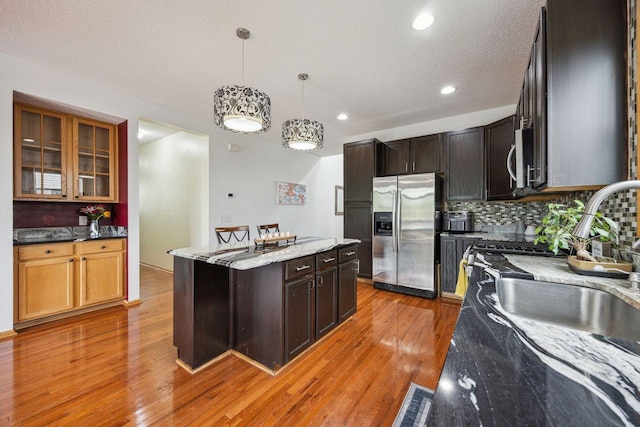 12332 3rd St NE, Blaine, MN 55434 - kitchen with appliances with stainless steel finishes, a center island, tasteful backsplash, light stone countertops, and light wood-style floors