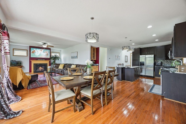 12332 3rd St NE, Blaine, MN 55434 - dining space with light wood-style floors, ceiling fan, a glass covered fireplace, and recessed lighting