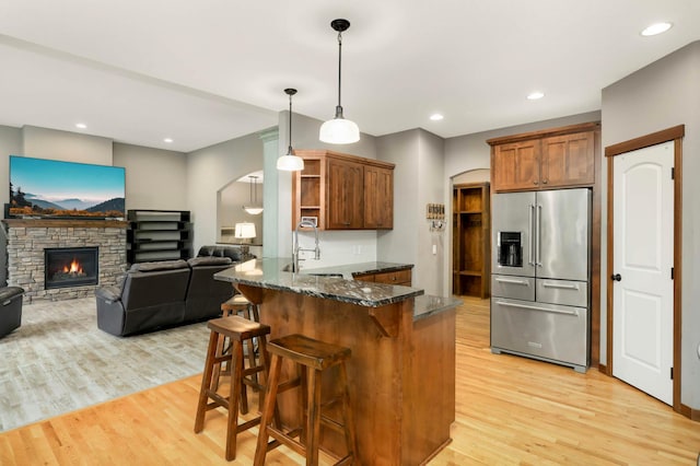 2349 175th Ln NE, Ham Lake, MN 55304 - kitchen featuring high end fridge, open shelves, a peninsula, light wood-style flooring, and arched walkways
