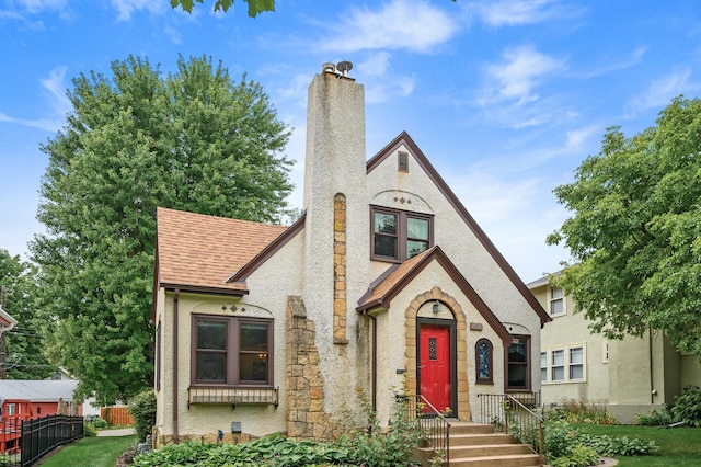 1928 Cleveland St NE, Minneapolis, MN 55418 - english style home featuring a chimney, stucco siding, a shingled roof, and stone siding