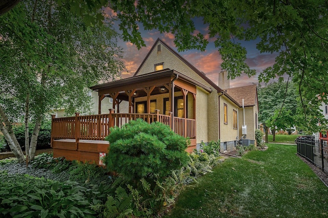 1928 Cleveland St NE, Minneapolis, MN 55418 - back of house at dusk featuring a yard, a chimney, central air condition unit, and stucco siding
