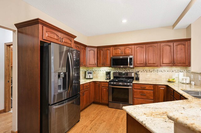 14550 Hunters Ln, Savage, MN 55378 - kitchen featuring appliances with stainless steel finishes, light wood-style flooring, light stone counters, and backsplash