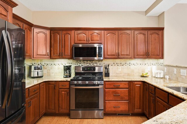 14550 Hunters Ln, Savage, MN 55378 - kitchen with stainless steel appliances, light stone countertops, and light wood finished floors