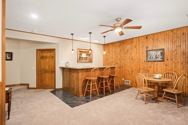 14550 Hunters Ln, Savage, MN 55378 - indoor wet bar featuring dark carpet, a ceiling fan, baseboards, wood walls, and hanging light fixtures
