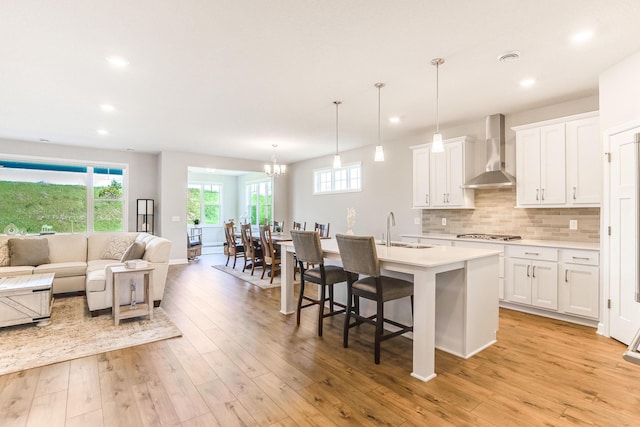 19171 Cottage Rd, Farmington, MN 55024 - kitchen featuring wall chimney exhaust hood, open floor plan, light countertops, a kitchen island with sink, and a chandelier