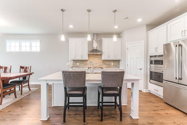 19171 Cottage Rd, Farmington, MN 55024 - kitchen featuring appliances with stainless steel finishes, wall chimney exhaust hood, a breakfast bar, light countertops, and decorative backsplash