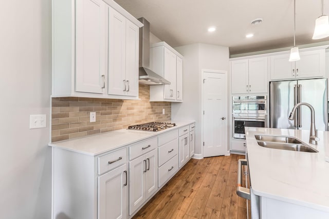 19171 Cottage Rd, Farmington, MN 55024 - kitchen featuring appliances with stainless steel finishes, wall chimney range hood, a sink, white cabinetry, and light wood-style flooring