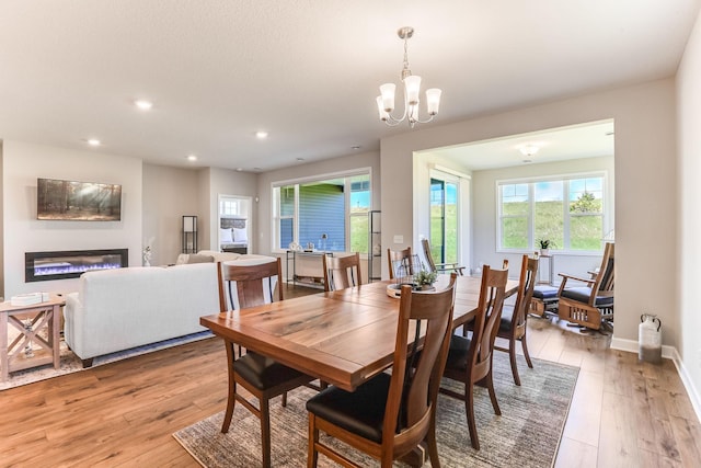 19171 Cottage Rd, Farmington, MN 55024 - dining area with light wood-style flooring, recessed lighting, a glass covered fireplace, a chandelier, and baseboards