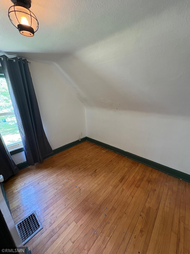 3934 Hubbard Ave N, Robbinsdale, MN 55422 - bonus room featuring vaulted ceiling, a textured ceiling, hardwood / wood-style flooring, and baseboards
