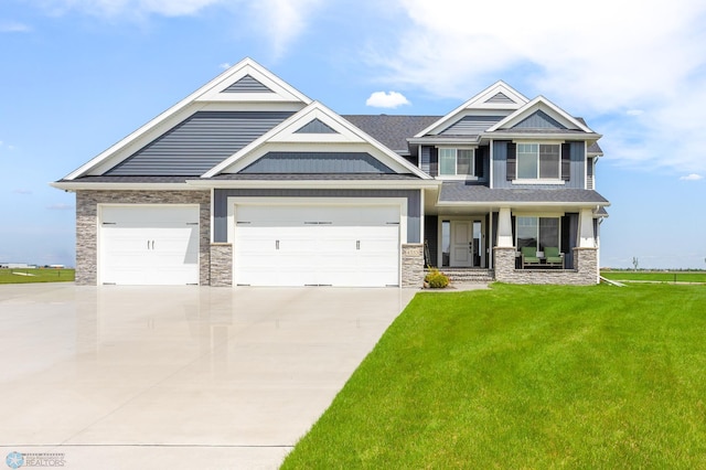 4533 38 1/2 Ave N, Reiles Acres, ND 58102 - craftsman house featuring concrete driveway, stone siding, an attached garage, a front yard, and a porch