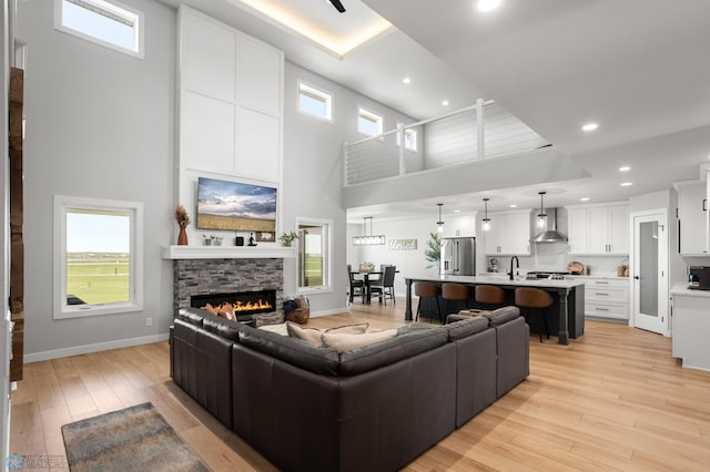 4533 38 1/2 Ave N, Reiles Acres, ND 58102 - living area with a high ceiling, a stone fireplace, light wood-style floors, baseboards, and recessed lighting