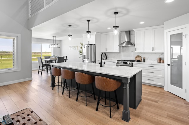 4533 38 1/2 Ave N, Reiles Acres, ND 58102 - kitchen featuring wall chimney exhaust hood, stainless steel appliances, a breakfast bar, a center island with sink, and white cabinets