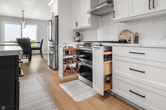 4533 38 1/2 Ave N, Reiles Acres, ND 58102 - kitchen with wall chimney range hood, appliances with stainless steel finishes, backsplash, light wood finished floors, and white cabinets