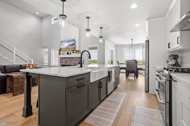 4533 38 1/2 Ave N, Reiles Acres, ND 58102 - kitchen featuring wall chimney exhaust hood, stainless steel appliances, a sink, white cabinets, and open floor plan