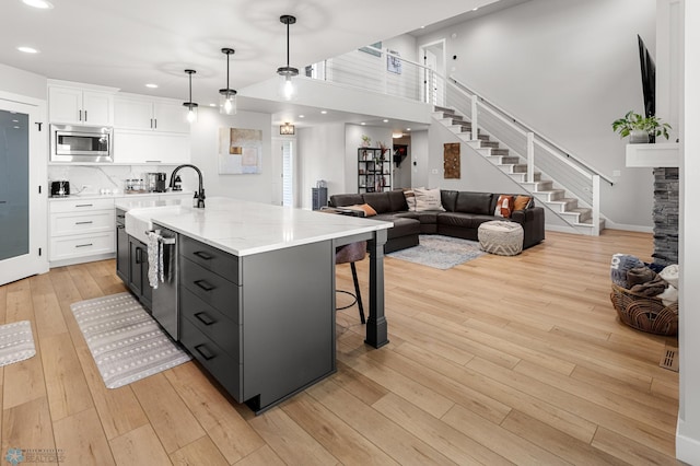 4533 38 1/2 Ave N, Reiles Acres, ND 58102 - kitchen with appliances with stainless steel finishes, white cabinetry, light wood-style floors, a sink, and a center island with sink