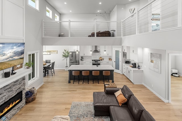 4533 38 1/2 Ave N, Reiles Acres, ND 58102 - living area with a towering ceiling, light wood-type flooring, recessed lighting, a fireplace, and baseboards